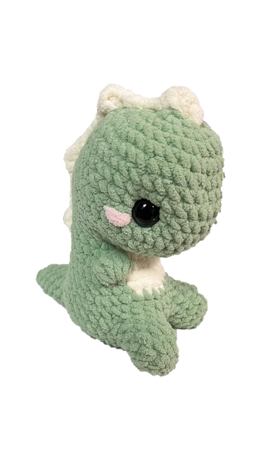 Green crochet dinosaur with soft spikes on its head and back looking right.