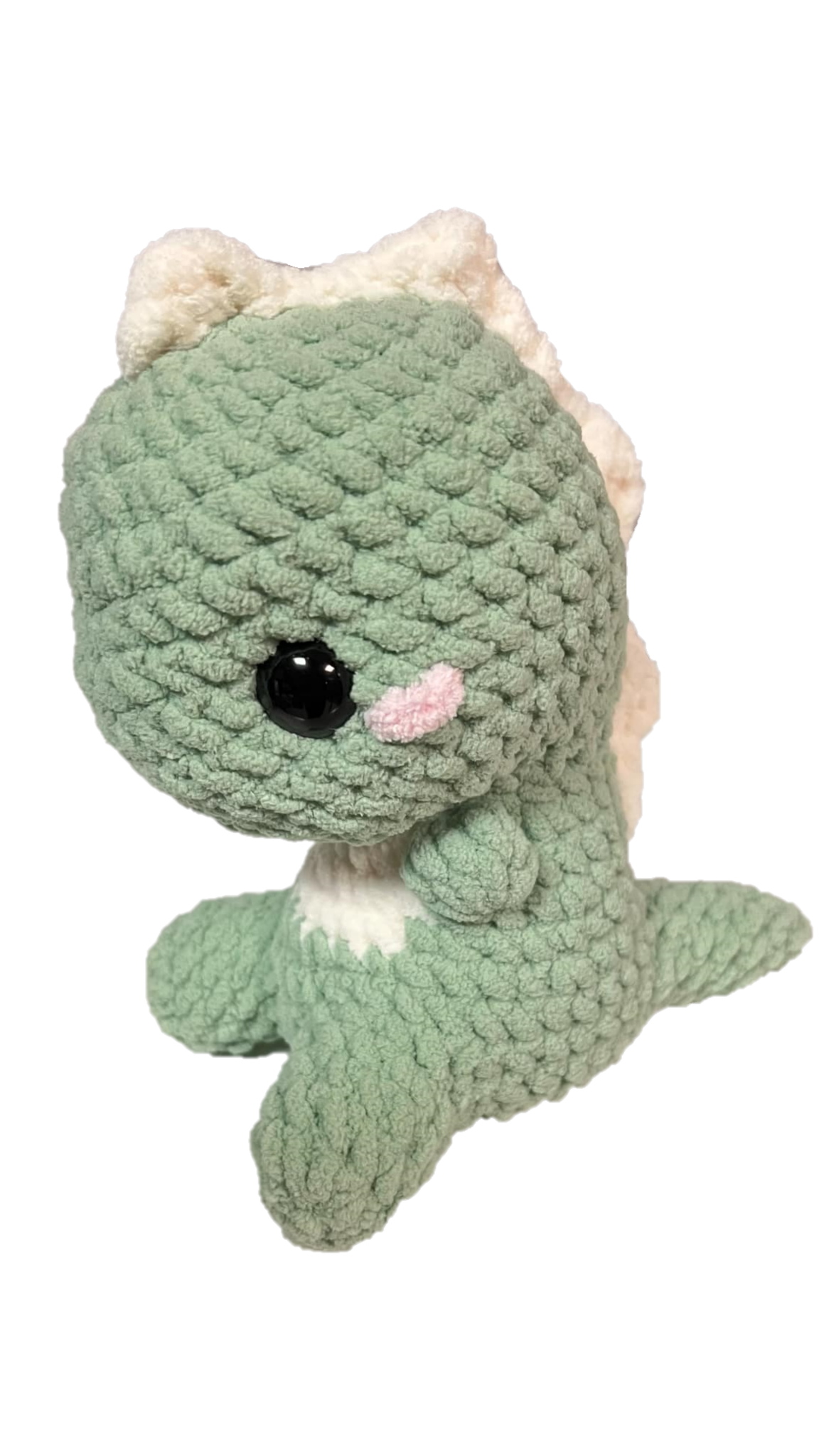 Green crochet dinosaur with soft spikes on its head and back looking left.