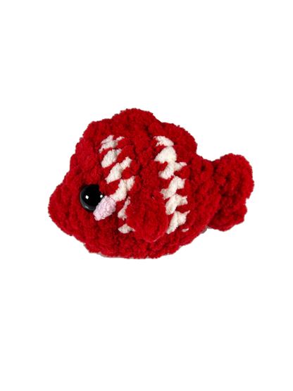 Red crochet fish plushie with 2 white stripes facing left.