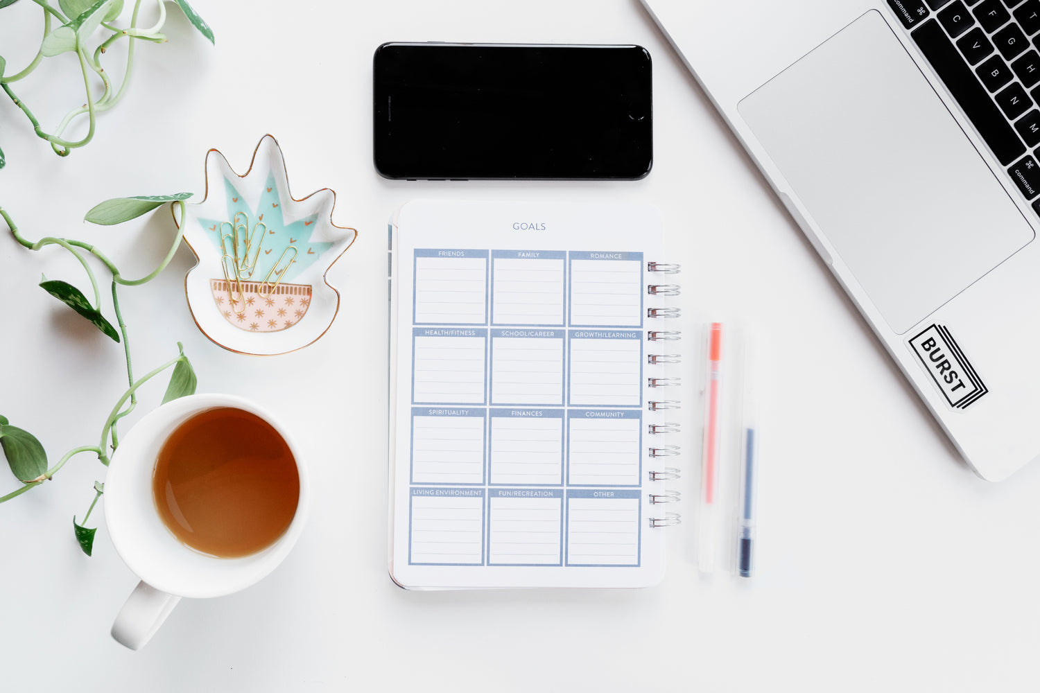 A planner with a laptop and office supplies next to it that says goals.